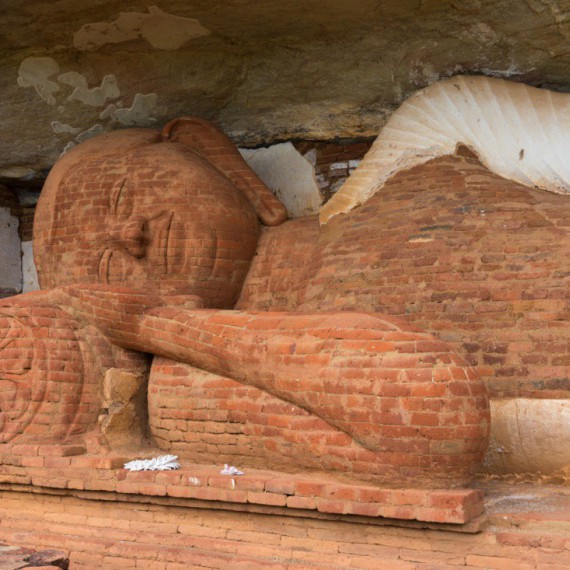 Socha spícího Buddhy pod skalou Pidurangala.