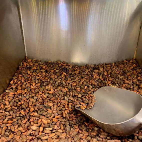 Naběračka ve velké nádobě plné kakaových bobů.