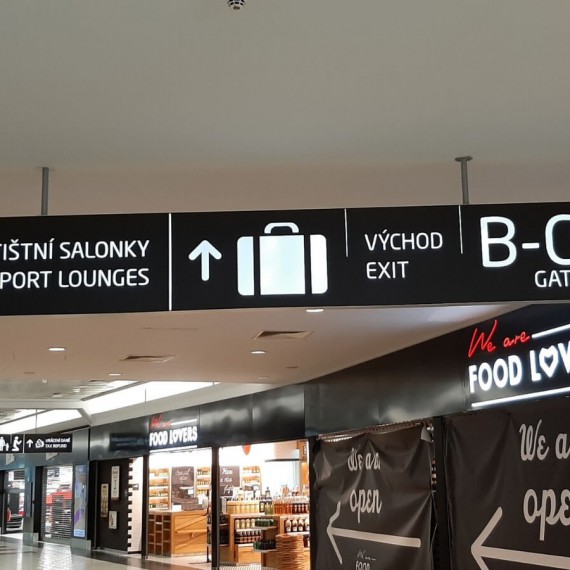 Obchody a směrové tabule na letišti v Praze.