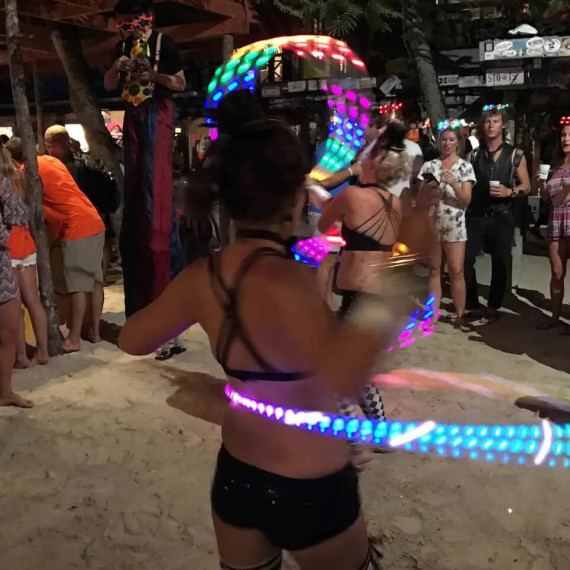 Silvestrovská oslava na ostrově Jost Van Dyke s tanečnicí s barevnými LED kruhy.