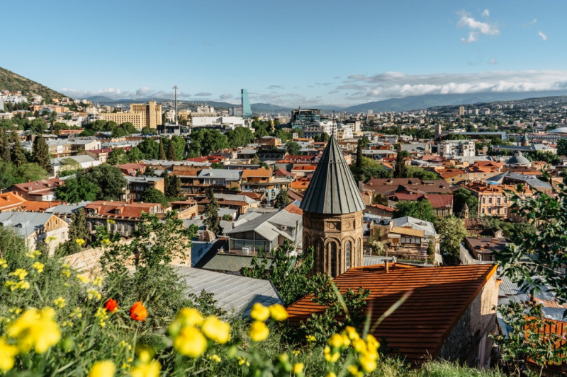 Město Tbilisi s mixem tradiční a moderní architektury, typickou kavkazskou estetikou a rušným městským životem.