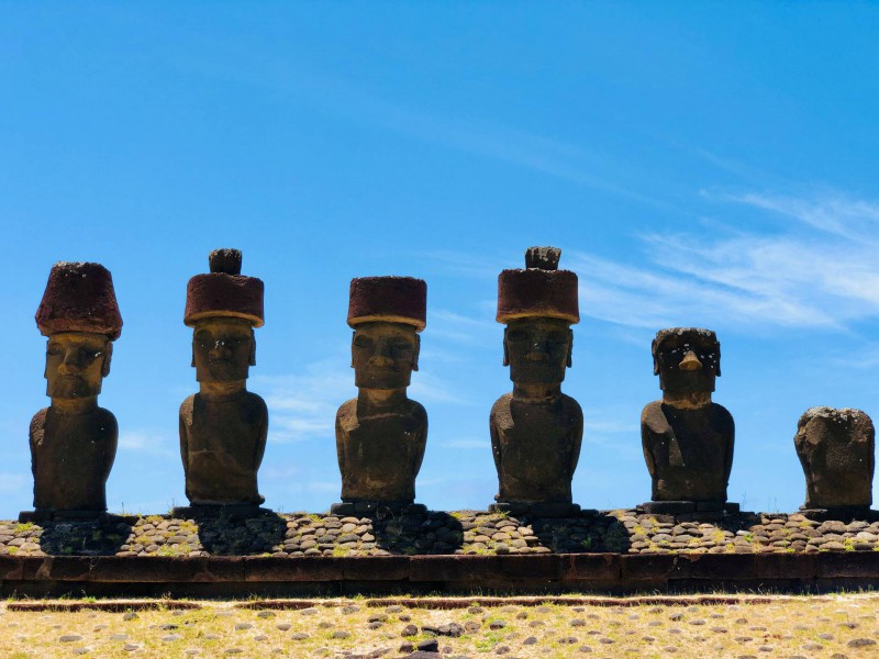 Šest soch Moai na kamenném podstavci.