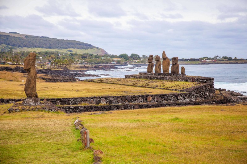 Sochy Moai s rozbouřeným mořem v pozadí.