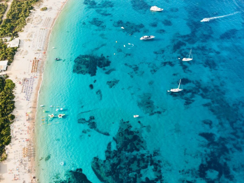 Bílá pláž s tyrkysovou vodou Cala di Volpe na Sardinii.