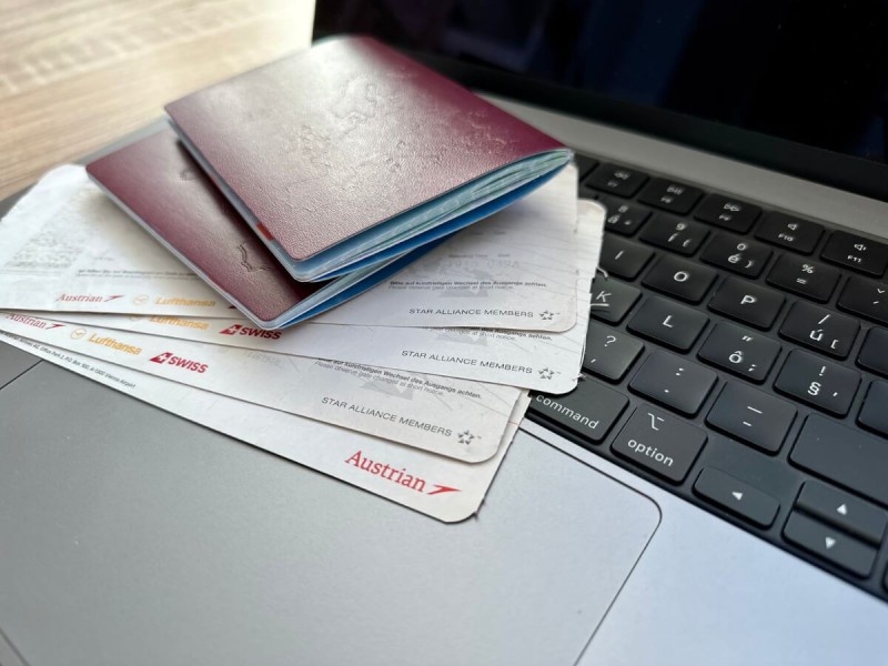 Cestovní doklady a letenky položené na notebooku.