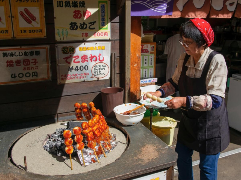 Japonka pripravuje grilované ryžové guľôčky yaki dango.
