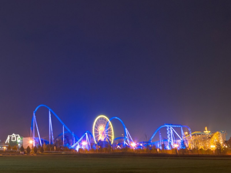 Osvětlené horské dráhy a kolotoče během noci v zábavním parku Europa-Park.