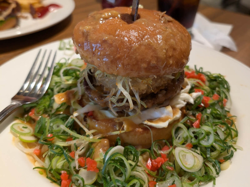 Japonský burger s masovou plackou, omáčkou a jarní cibulkou.