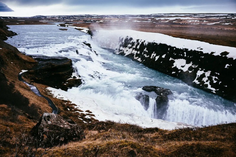 Zasněžená krajina a divoká voda vodopádu Gullfoss.