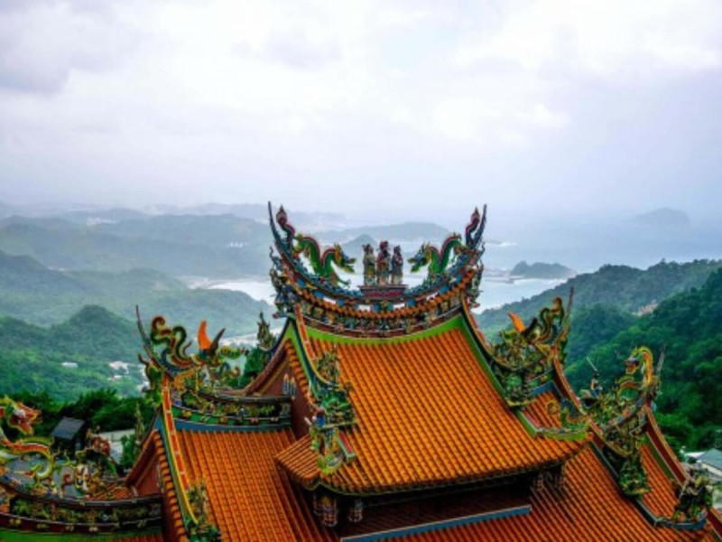 Chrám s dračími ornamenty v Jiufenu s výhledem na kopce a moře.