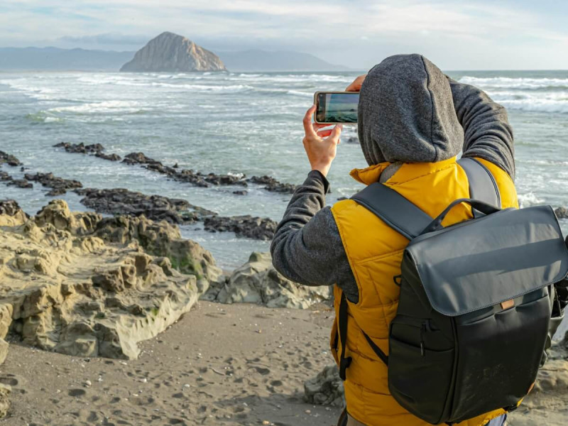 Turista fotografuje oceán na pobřeží Morro Bay v Kalifornii.