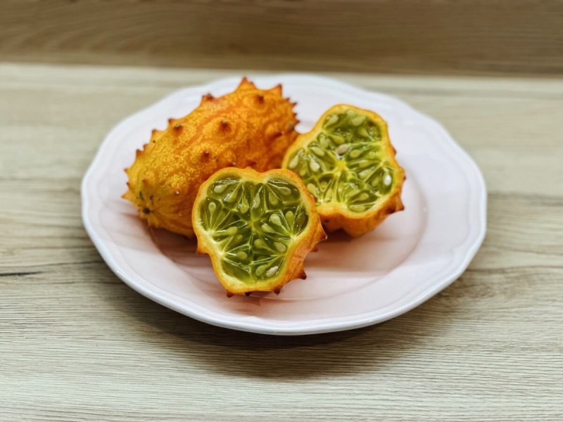 Oranžové ovoce kiwano s trny a zelenou dužinou.