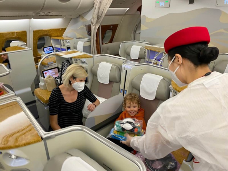 Letuška v letadle předávající dítěti malé dárky od společnosti Emirates.