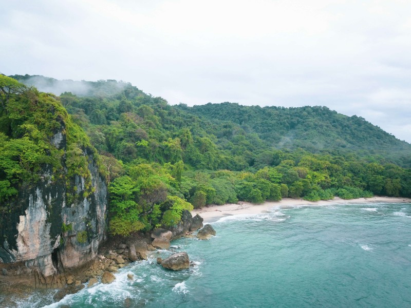Bílá pláž s pralesem v pozadí v Mal Pais, Kostarika.