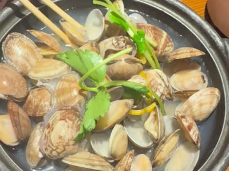 Mušle asari ve vývaru s bylinkami a citrusy v japonské misce.