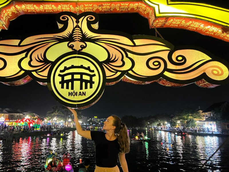 Průvodkyně CK SEN pod osvětleným znakem Hoi An na mostě nad řekou Thu Bồn.