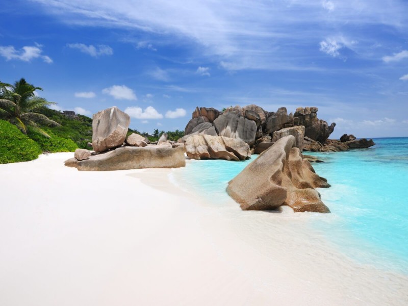 Bílá pláž s tyrkysovou vodou na Seychelech.