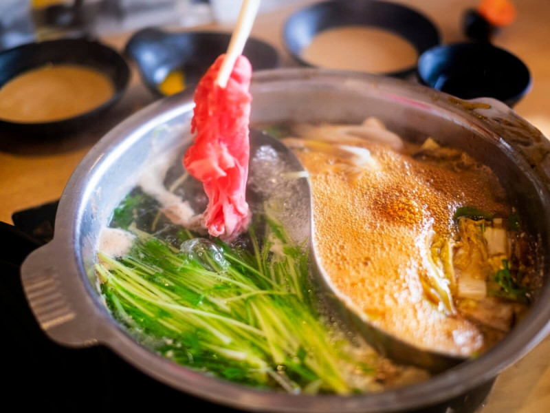 Hrnec shabu-shabu a hůlky s masem.