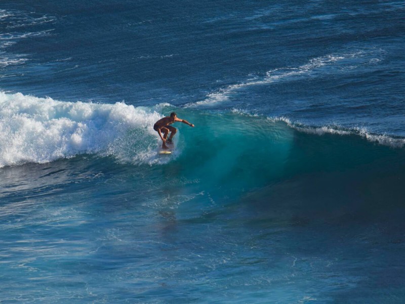Surfař jezdící na vlně v Uluwatu na Bali.