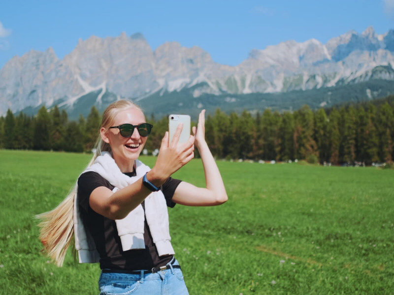 Volání z mobilního telefonu na louce s horami v pozadí.