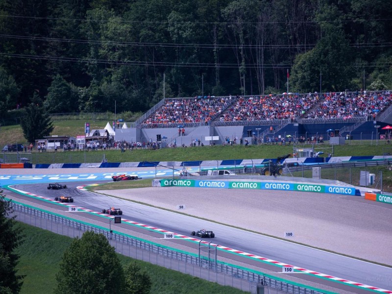 Závod Formule 1 a plná tribuna fanoušků.