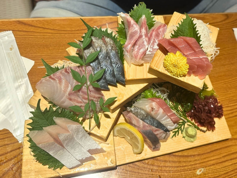 Výběr sashimi z více druhů ryb servírovaný na dřevěném podnose.