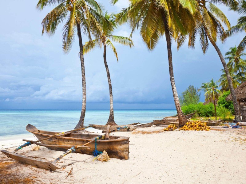 Bílá pláž a dřevěné loďky na Zanzibaru.