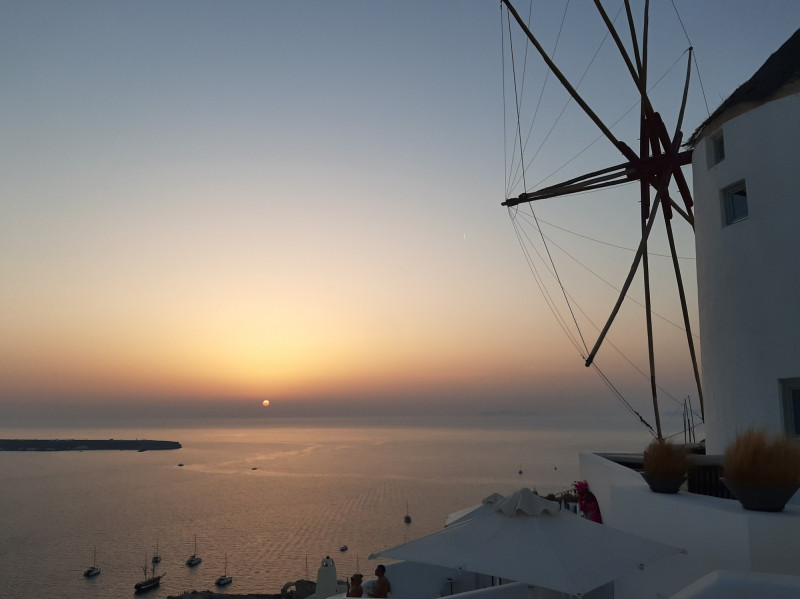 Západ slunce nad větrným mlýnem v malebné obci Oia.