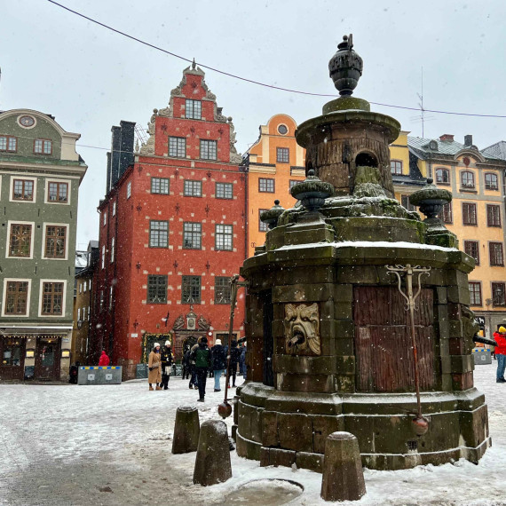 Zasněžené náměstí Stortoget plné barevných domků.