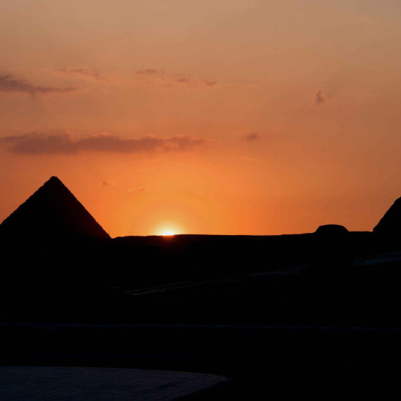 Dechberoucí západ slunce nad pyramidami.