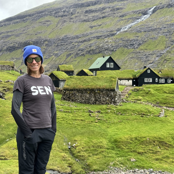 Zelené kopce a tradiční dřevěné domky na Faerských ostrovech.