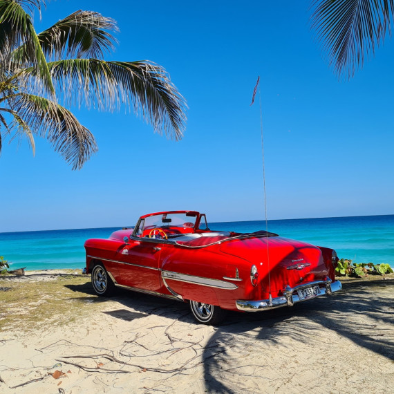 Pláž na Kubě s červeným veteránem.